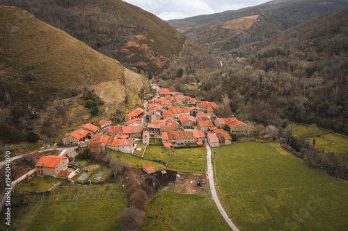 Stunning aerial drone perspective of Barcena Mayor, a historic mountain village in Cantabria. The image showcases the traditional stone houses.