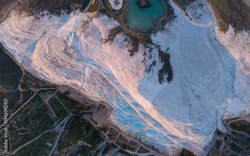 Aerial drone view of the famous Pamukkale travertines and thermal pools in Denizli, Turkey, showing the white calcium terraces, natural formations, and scenic landscape from above.