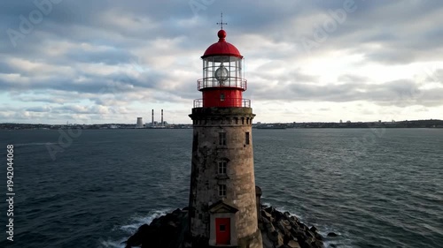 Dramatic Lighthouse Standing Proudly in the Middle of the Ocean Under Cloudy Skies.