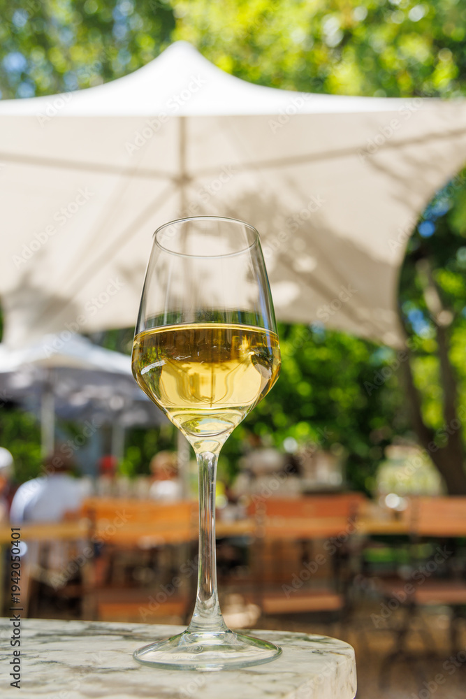 Naklejka premium Glass of white wine on sunny terrace