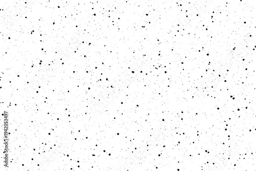 Countless tiny black particles are randomly dispersed across a bright clean white sheet