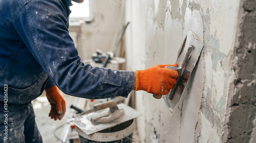 Construction Worker Plastering Interior Wall With Trowel Wearing Orange Gloves During Renovation