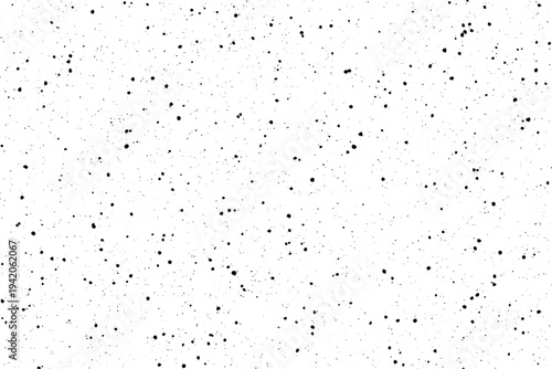 Tiny black speckles scattered randomly across a bright white surface forming a subtle granular pattern