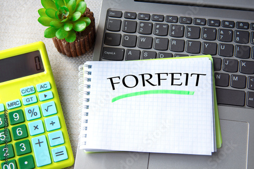 Foto FORFEIT - word in notepad with laptop, calculator and cactus in the background