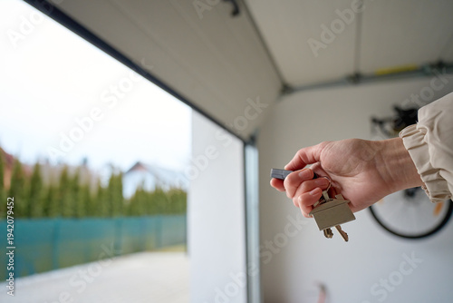 Cuadro en lienzo Closeup of hand holding garage remote and keys inside garage with open door