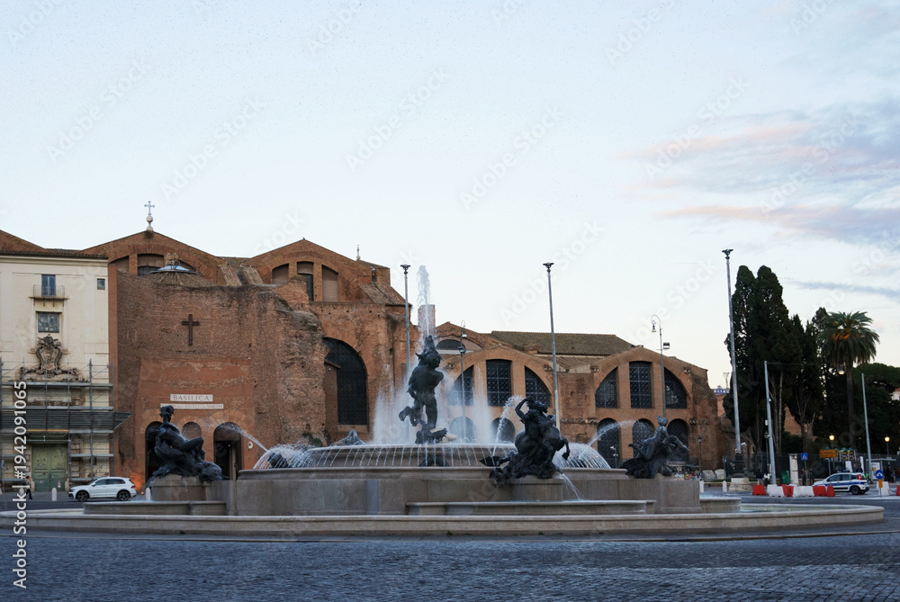 Obraz premium Piazza della Repubblica in Rome, Italy. In the center is the Fountain of the Naiads, and in the background stands the Basilica of Santa Maria degli Angeli e dei Martiri.
