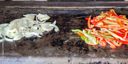 Obraz na plátně Sliced onions and peppers on a professional iron griddle