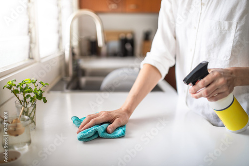Woman Cleaning Kitchen Countertop With Spray and Cloth