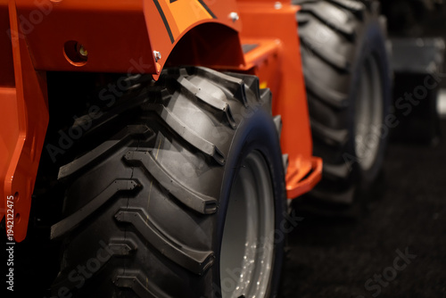 Принти на полотні Heavy equipment wheel and deep tread detail with orange machine body, ideal for