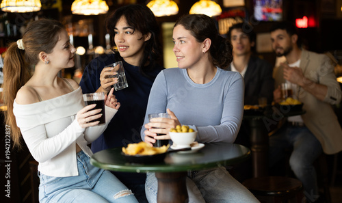 Tableau sur toile Smiling women friends have fun and drinking beer on party in bar