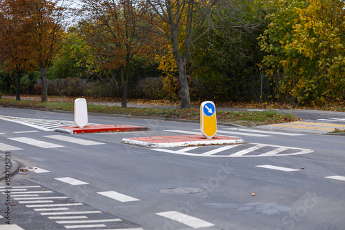 Engineering traffic calming measures with elevated pedestrian refuge island and directional signage on asphalt road. Urban road design for speed reduction and safety enhancement