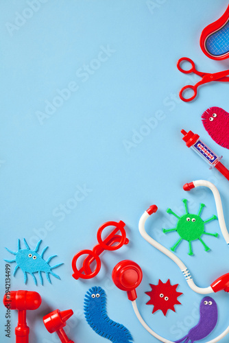 Vertical composition of kids doctor toy kit and colorful felt microbes on blue. Ideal for pediatric medical blog, children's health advertising, and vaccination campaign