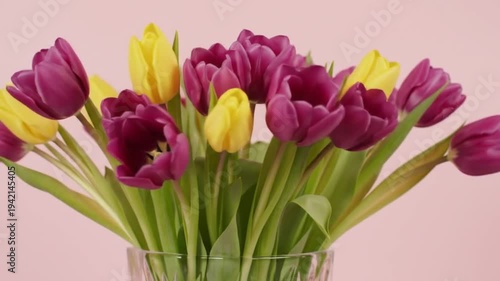 Bunch of vibrant purple and yellow tulips in a clear vase.