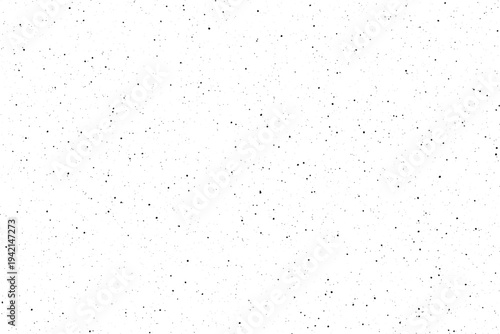 Numerous tiny black speckles create a granular texture across a clean white surface with subtle scattered elements