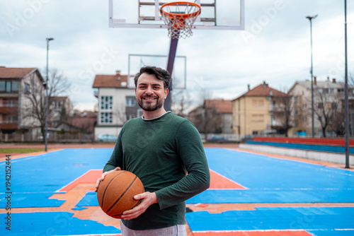 фотографія Man stands with basketball on court in city during cloudy day