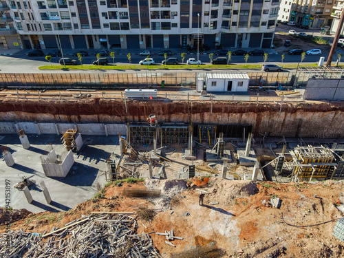 Aerial drone view of a large residential real estate development and construction site with cranes, foundations, and heavy machinery in Agadir, Morocco.