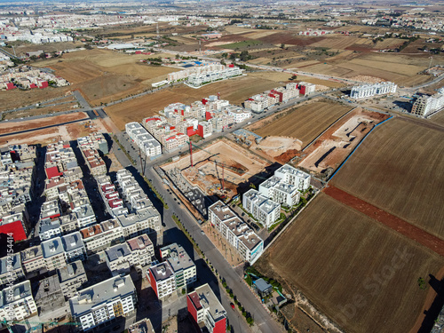 Aerial drone view of a large residential real estate development and construction site with cranes, foundations, and heavy machinery in Agadir, Morocco.