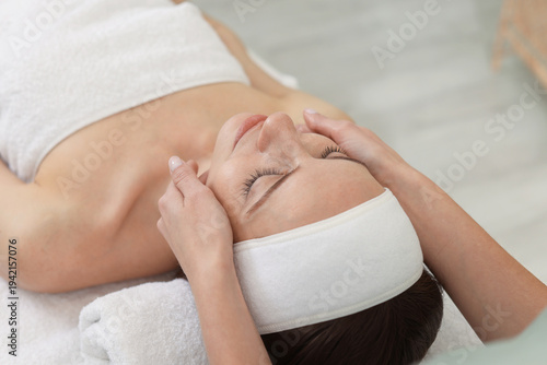 Fotografija Beautiful woman in spa headband receiving facial massage on couch indoors, close