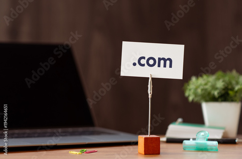 Modern technology concept of .com on card with laptop, clips. Digital innovation and connectivity visualization.