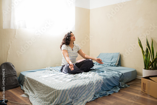 Woman finding peace and balance, meditating in apartment room with minimal furniture, embracing new beginnings