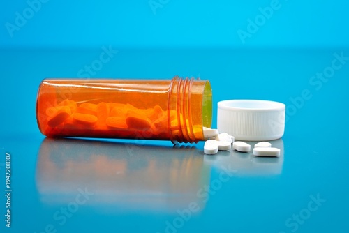 Tableau sur toile Medication White Pills and  Orange Plastic Container Blue Background