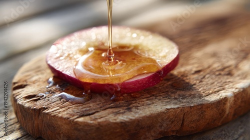 Golden honey dripping onto a fresh red apple slice on rustic wood