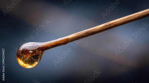 Golden honey drop on a wooden spoon