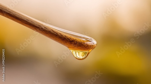 Golden honey drop on a wooden utensil macro