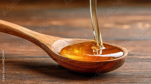 Golden honey pouring into a wooden spoon on a wooden table