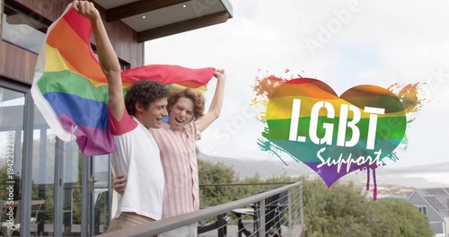 Holding two adult men on balcony, wearing raglan tee, showing LGBT Support heart and pride flag