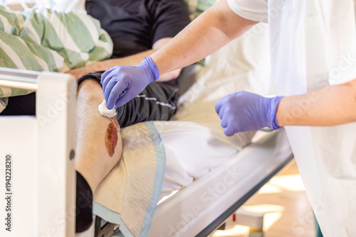 Nurse disinfecting simulated wound on patient leg during nursing training and wound care instruction