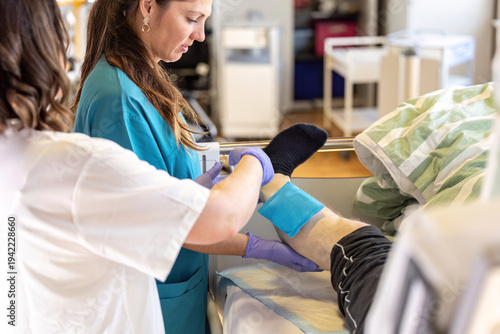 Nurse applying absorbent dressing to patient leg wound during clinical wound care treatment in hospital