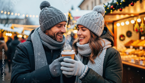 Cozy Christmas Moment: A warm embrace between a couple amidst a festive christmas market, enjoying hot beverages and the holiday spirit.