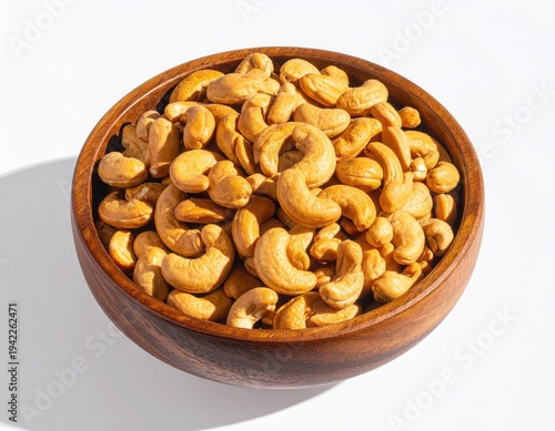 Top view of Roasted cashew nuts in wooden bowl with pile of cashew nuts on white background.