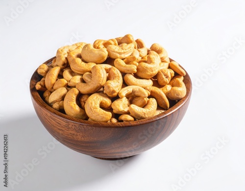 Top view of Roasted cashew nuts in wooden bowl with pile of cashew nuts on white background.