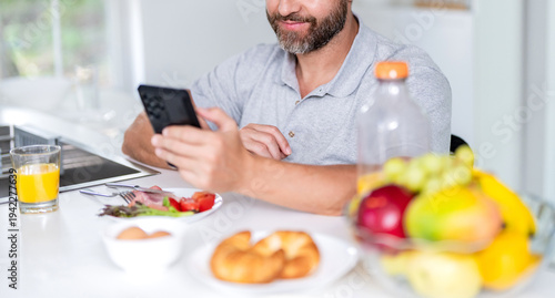 Man cropped view eating cereal with milk. Healthy food online. Man eat morning breakfast in kitchen. Business man eating morning breakfast. Morning at home with phone. Breakfast in kitchen