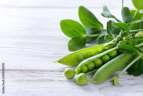 Fresh green peas with pods and leaves on white wooden table