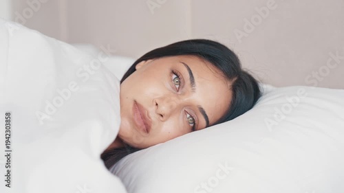 Attractive Female Face With Healthy Glowing Skin Smiling. Adult Girl Gently While Lying on White Pillow. Young Woman During Morning Wake Up Routine at Home Slow Motion 4k