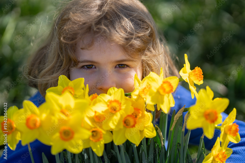 Fototapeta premium Spring fun for kids. Child play outdoors in a beautiful spring garden. Kid face in flowers. Adorable little kid in blooming cherry garden on beautiful spring day. Happy child during spring blossom.