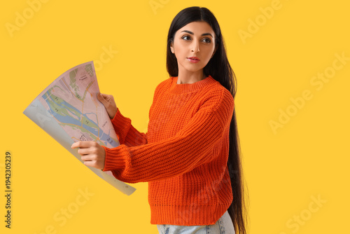 Young woman with map on yel...