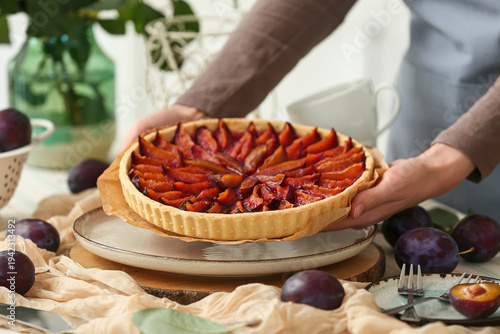 Woman holding tasty plum pi...