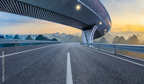 Empty asphalt highway leading to karst mountain peaks at sunset in Guilin, Guangxi, China.