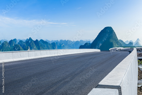 Empty asphalt highway and karst mountain landscape under a blue sky in Guilin, China.