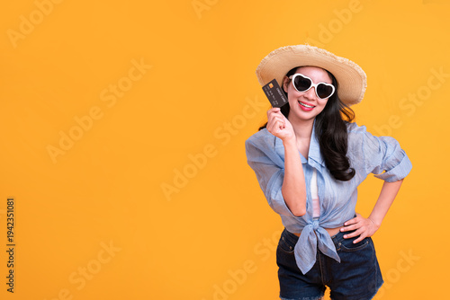 Happy Asian woman woman tourist showing credit card isolated on orange background.