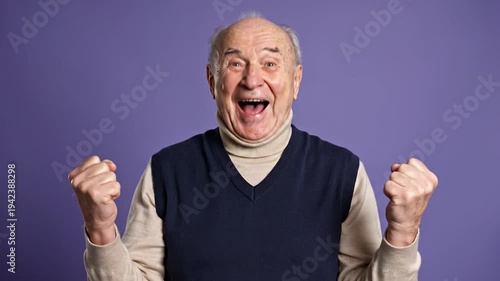 Excited elderly man celebrating with fists clenched and mouth open