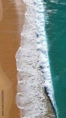 Aerial view of ocean waves gently washing onto a sandy shore
