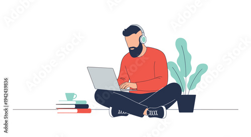 Bearded man sitting cross-legged on the floor working on a laptop computer while wearing headphones for focused study.