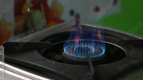 A rural Indian woman cooking on an LPG gas stove in a simple kitchen. The image highlights rising cooking gas prices, energy crisis