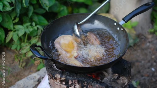 Cooking Delicious Fried Chicken on Outdoor Stove with Frying Pan and Juicy Ingredients Surrounded by Green Plants and Natural Setting