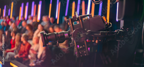 Professional broadcast camera filming live TV show with blurred audience and copy space